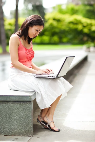 Mulher no telefone e trabalhando em seu laptop — Fotografia de Stock
