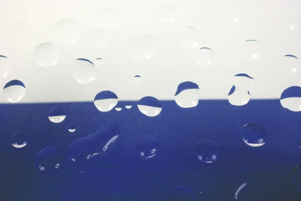 Vatten droppar på blå bakgrund — Stockfoto