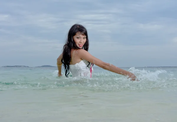 Hübsche junge Frau mit Armen planscht das Meerwasser an einem freien Strand in Para — Stockfoto