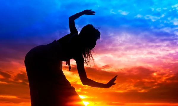 Σιλουέτα της γυναίκας πραγματοποιεί ως χορευτής, κατά τη διάρκεια του ηλιοβασιλέματος Εικόνα Αρχείου