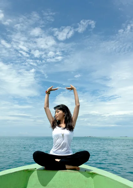 Bella giovane donna si esibisce come mossa yoga di fronte alla barca durante le vacanze a Foto Stock Royalty Free