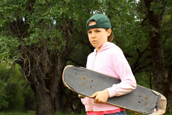 Молодая девушка с хорошо используемым скейтбордом — стоковое фото