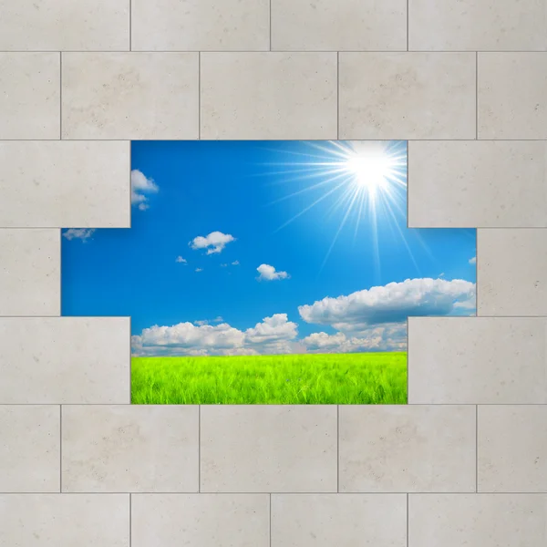 Šedá zeď vidět zelená pole a modré nebe — Stock fotografie