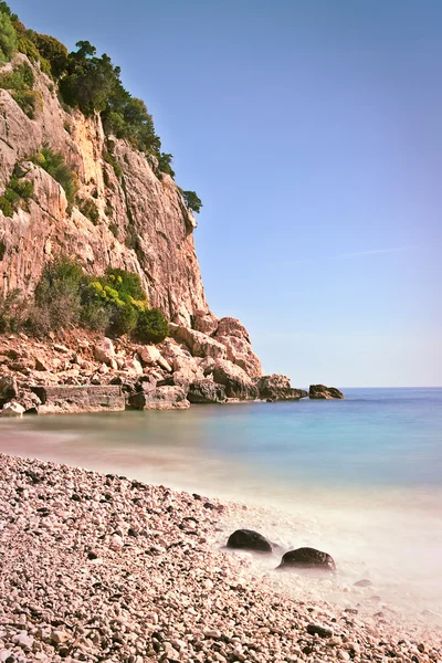 Praia rochosa falésias altas mar azul — Fotografia de Stock