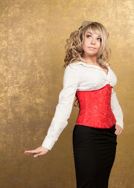 Sexy blonde woman in corset and skirt on golden background — Stock Photo, Image