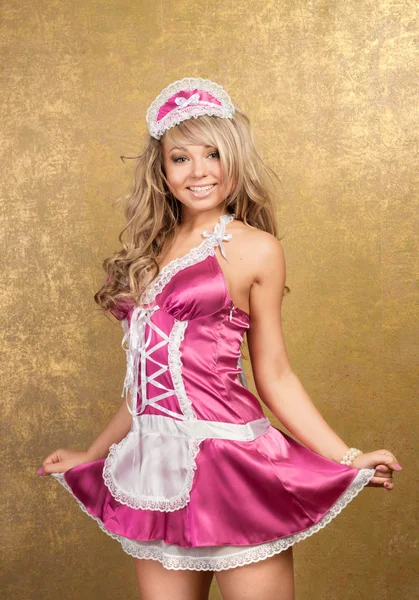 金色の背景にピンクの魅惑的なドレスでセクシーなブロンドの女性 — ストック写真