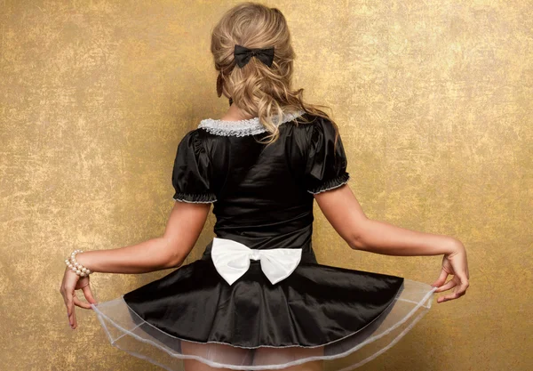 Sexy blondýnka ve svůdné černé šaty na zlatém pozadí — Stock fotografie