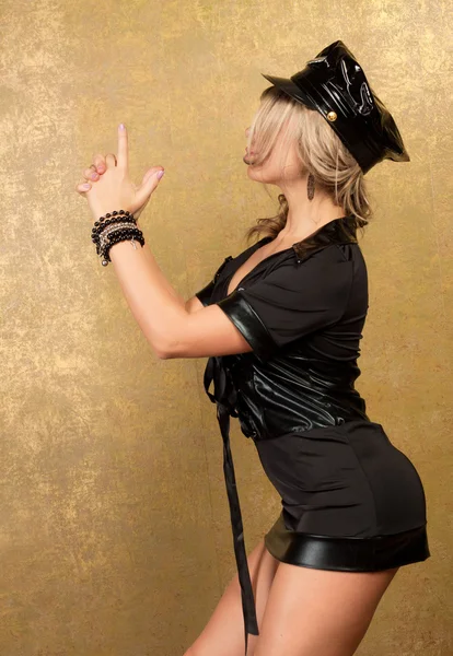 Sexy blonde frau im schwarzen polizei kostüm auf goldenen hintergrund — Stockfoto