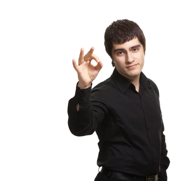 Portrait of young man in black shirt gesturing ok sign against w — Stock Photo, Image