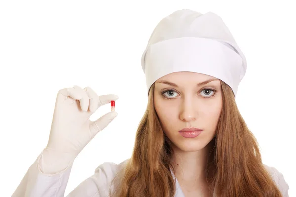 Unga läkare med röda piller i händerna på vit bakgrund — Stockfoto