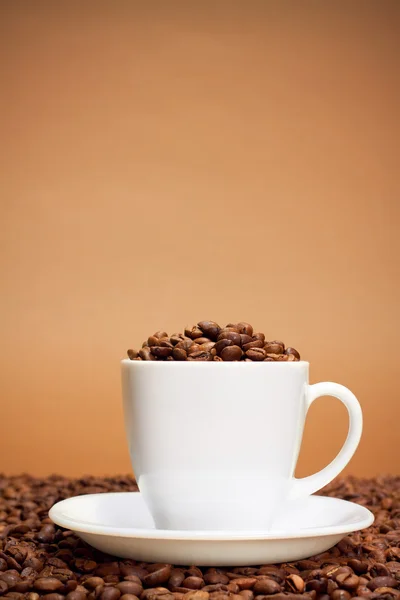 Beyaz fincan kahve çekirdekleri ile dolu — Stok fotoğraf