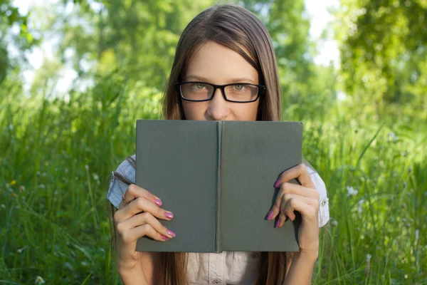 Ung student tjej sitter i parken med bok — Stockfoto