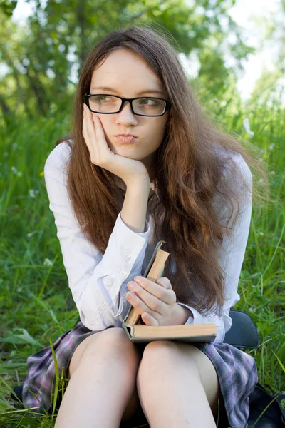 Chica joven estudiante sentada en el parque con el libro — Foto de Stock