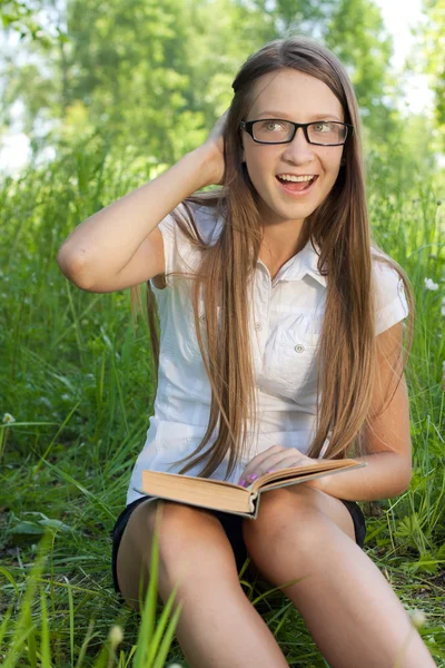 Jonge student meisje zit in park met boek — Stockfoto