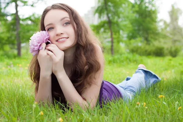 Jovem adolescente bonita com flor rosa no gramado — Fotografia de Stock
