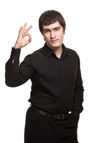 Portrét mladého muže, v černé košili ukázal ok znamení proti w — Stock fotografie