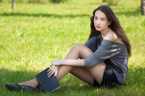 Young student girl sitting in park with book — Stock Photo, Image