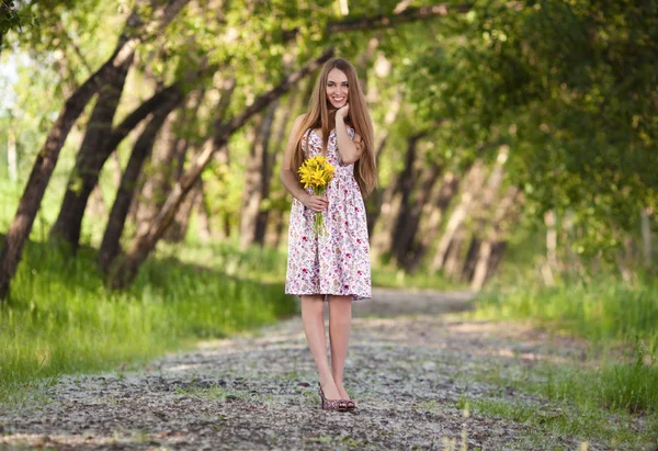 Retrato de una bella mujer rubia con flores amarillas al aire libre — Foto de Stock