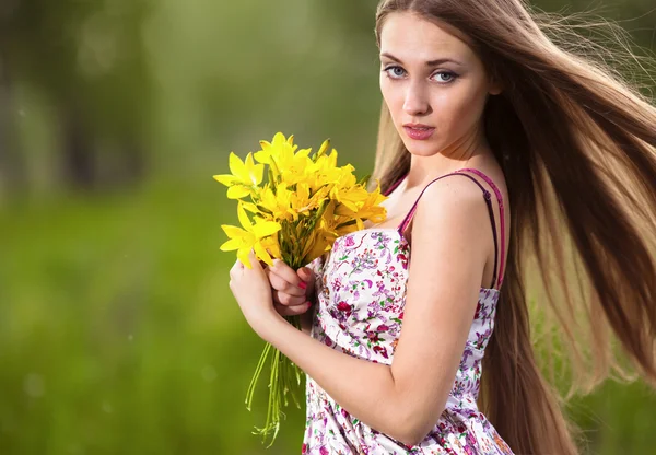 Portret van een mooie blonde vrouw met gele bloemen buiten — Stockfoto