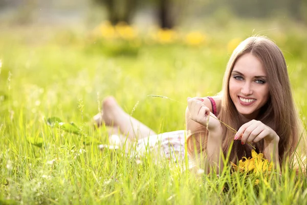 Schöne junge blonde frau auf der wiese an einem warmen sommertag — Stockfoto