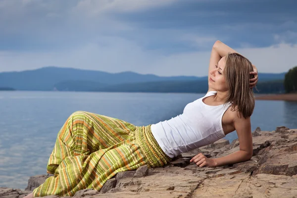 Mooie gelukkig vrouw zitten op rots boven zee bij zomer storm d — Stockfoto