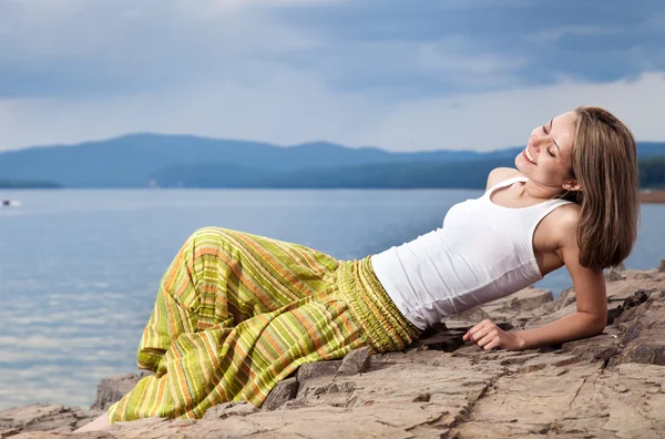 Beautiful happy woman sitting on rock over sea at summer storm d — Stock Photo, Image