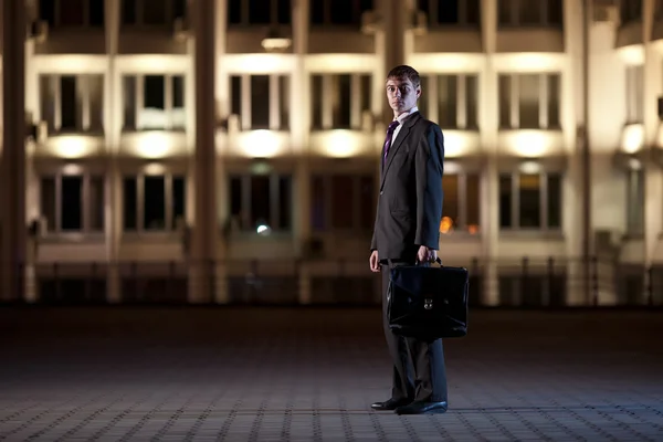 Knappe zakenman met werkmap bij nacht city in de backgro — Stockfoto