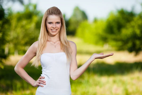 Beautiful young blonde woman in park holding anything — Stock Photo, Image