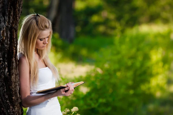 Attraktiv ung kvinna läsa bok i parken — Stockfoto
