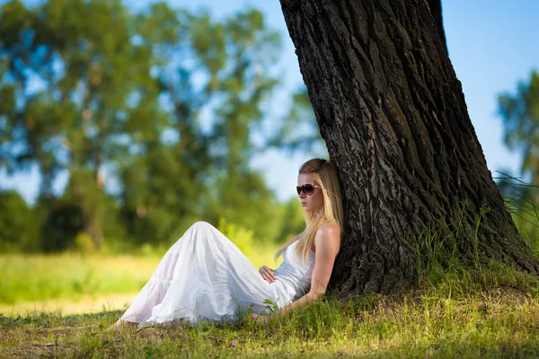 Genç sarışın bir kadın beyaz elbiseli rahatlatıcı Park — Stok fotoğraf