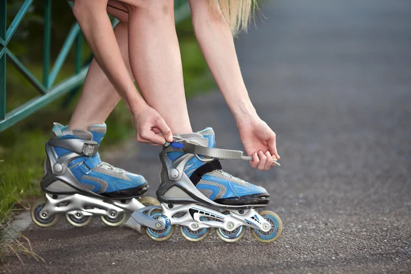 stock image Young woman put on roller-skate close up