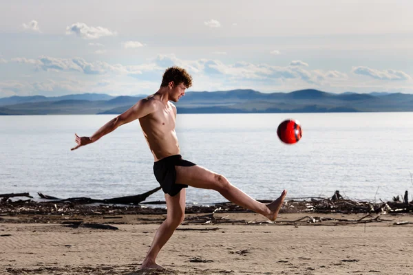 Silny mężczyzna seksowny kopać piłki na plaży — Zdjęcie stockowe