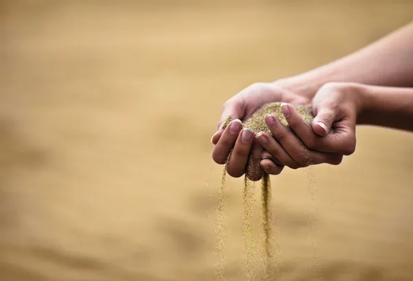 Молодая женщина с песком в руках — стоковое фото