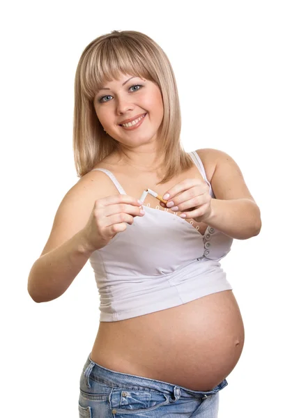 Молода вагітна жінка тримає зламану сигарету, стоячи — стокове фото