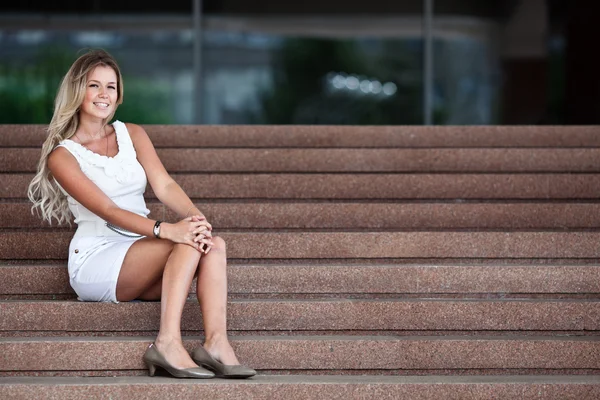 Aantrekkelijke jonge vrouw zittend op een trap van een office-build — Stockfoto
