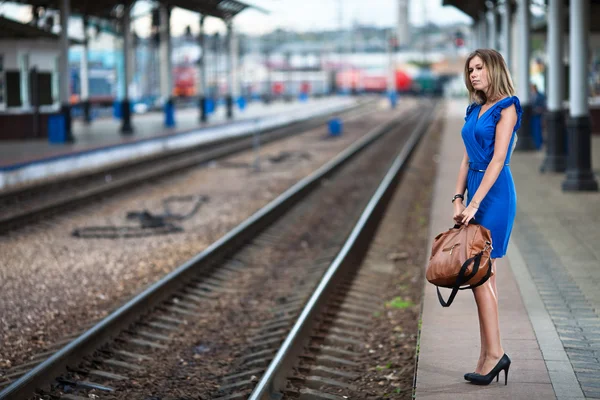 Привлекательная дама ждет поезд на платформе железнодорожного вокзала — стоковое фото