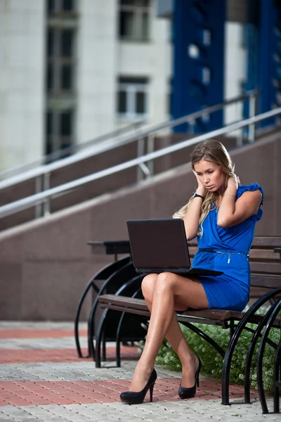 Senhora elegante atraente com laptop sentado num banco em ci — Fotografia de Stock