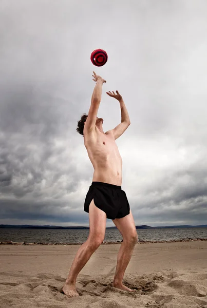 Silne seksowny mężczyzna z czerwoną piłkę na plaży — Zdjęcie stockowe