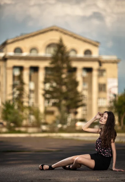 Jonge vrouw die aan de straat van stad zit — Stockfoto