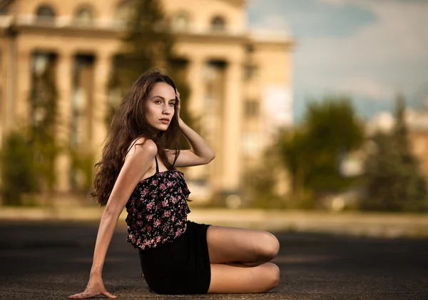 Młoda kobieta siedząca przy ulicy w mieście — Zdjęcie stockowe