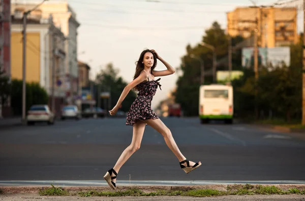 Unbekümmerte junge Frau springt in der Stadt auf die Straße — Stockfoto