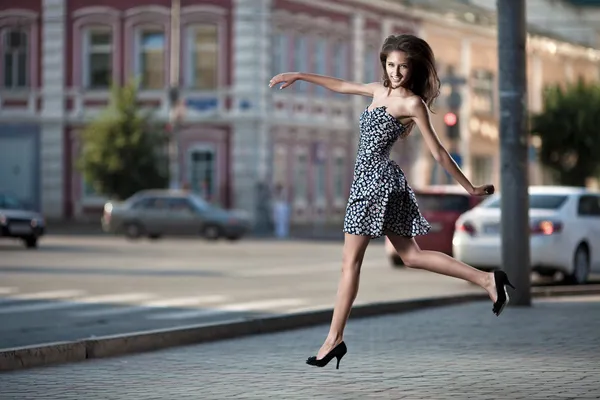 Молодая беззаботная женщина, прыгающая на улице в городе — стоковое фото