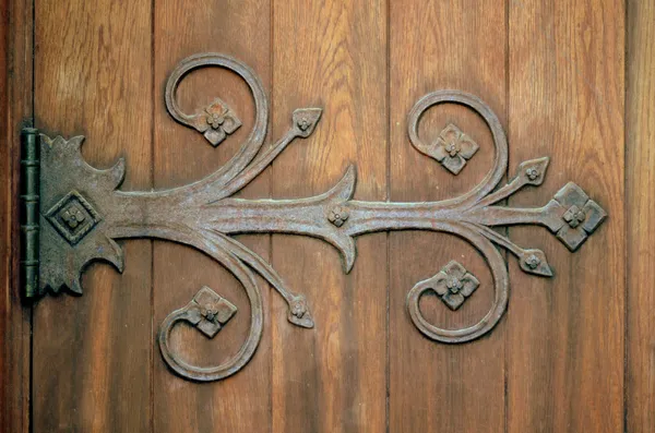 Ozdobné železné závěs na staré dřevěné dveře — Stock fotografie