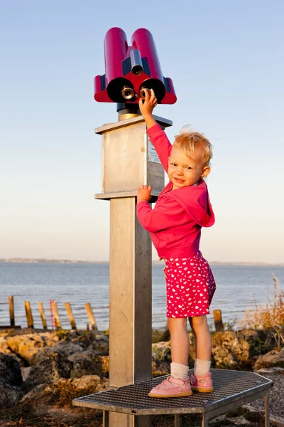Standing little girl by telescope — Stock Photo, Image