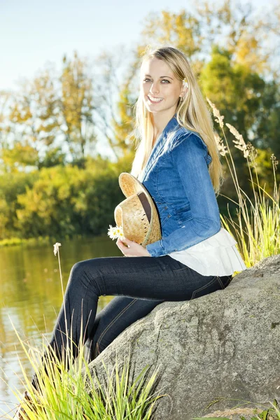 Giovane donna seduta su pietra allo stagno — Foto Stock