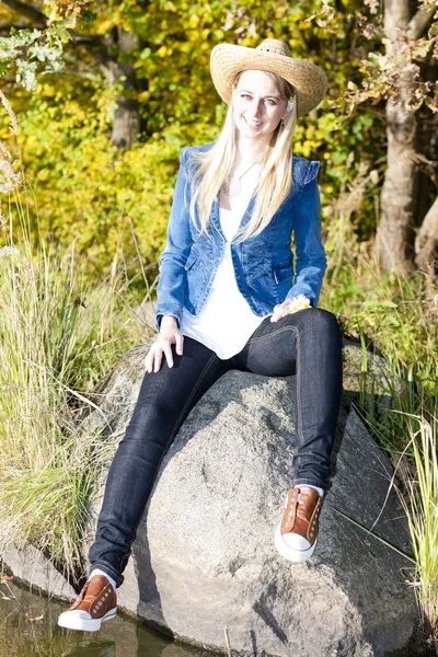 Jonge vrouw zitten op steen — Stockfoto