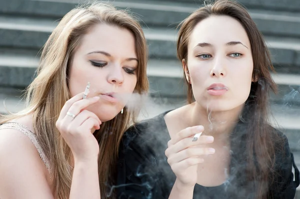 Дві сумні молоді дівчата курять — стокове фото