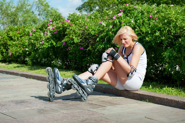 Blond kobieta ma trafić na łyżwach na deskorolkami jak również kolana — Zdjęcie stockowe