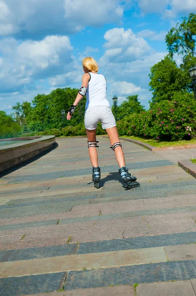 Menina loira em passeios de patins — Fotografia de Stock