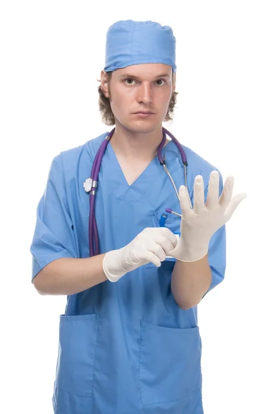 El joven doctor se pone guantes quirúrgicos. Fotos De Stock